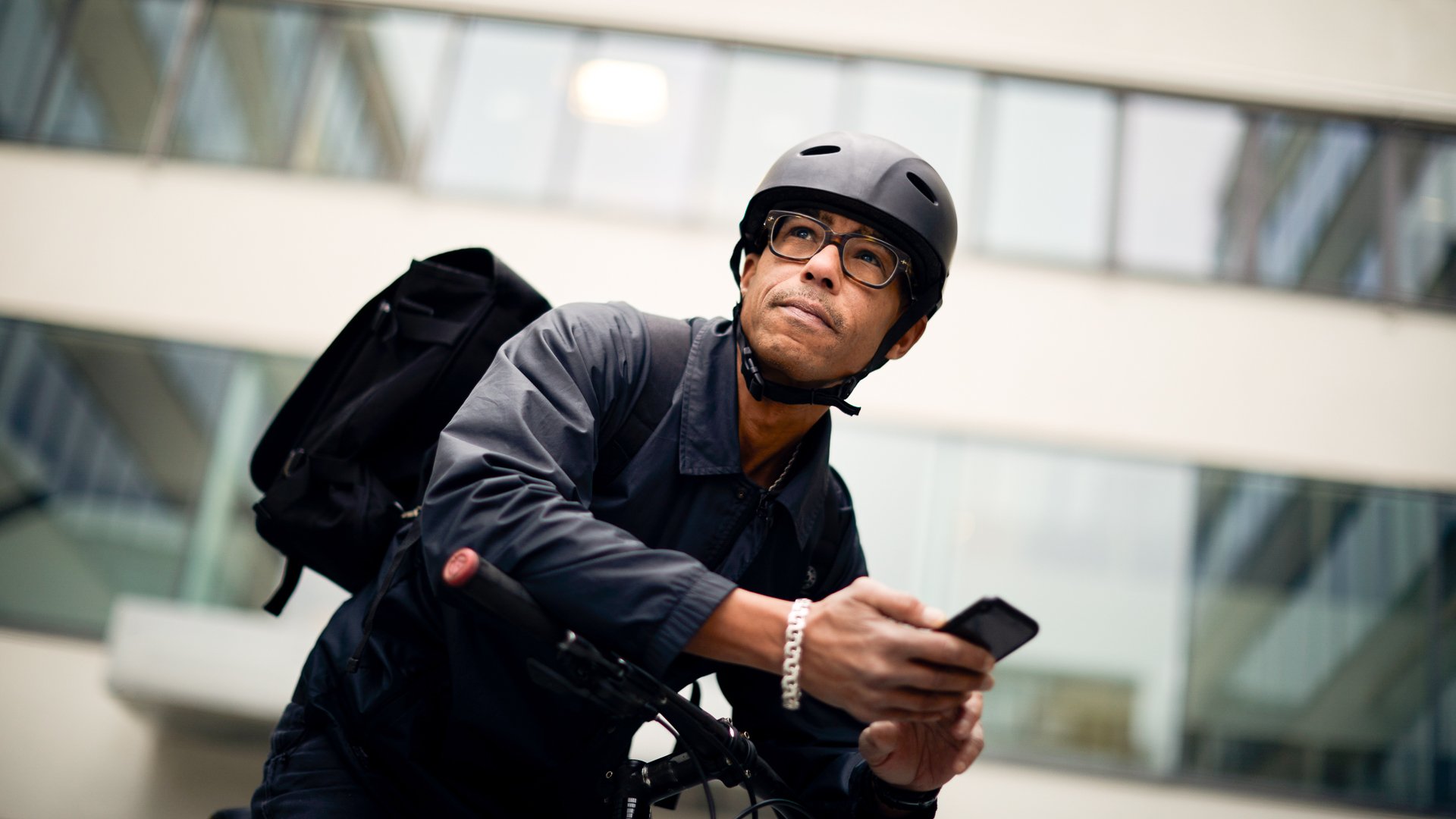 Man med cykelhjälm som håller i en mobiltelefon