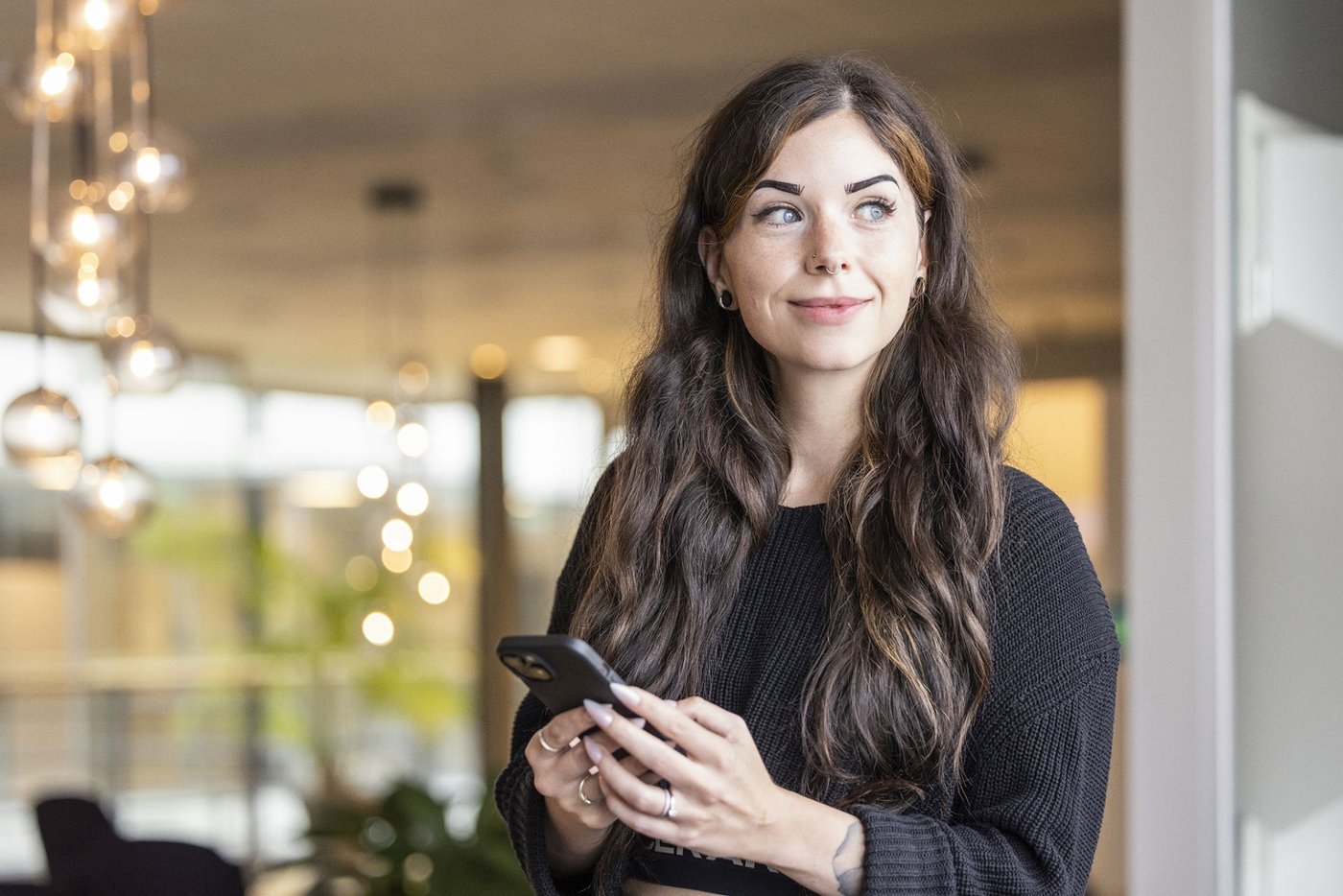 Kvinnlig medarbetare som tittar åt sidan medan hon håller i sin telefon