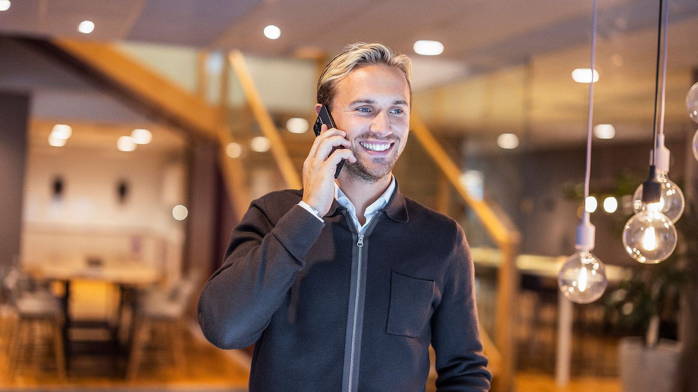 Manlig medarberae som skrattar och pratar i telefon
