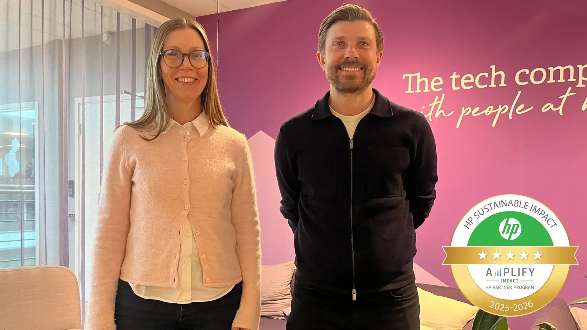 En kvinna och en man står framför en vägg med texten “The tech company with people at heart”. Ett emblem visar att Advania är certifierad för HP Amplify Impact 2025–2026.