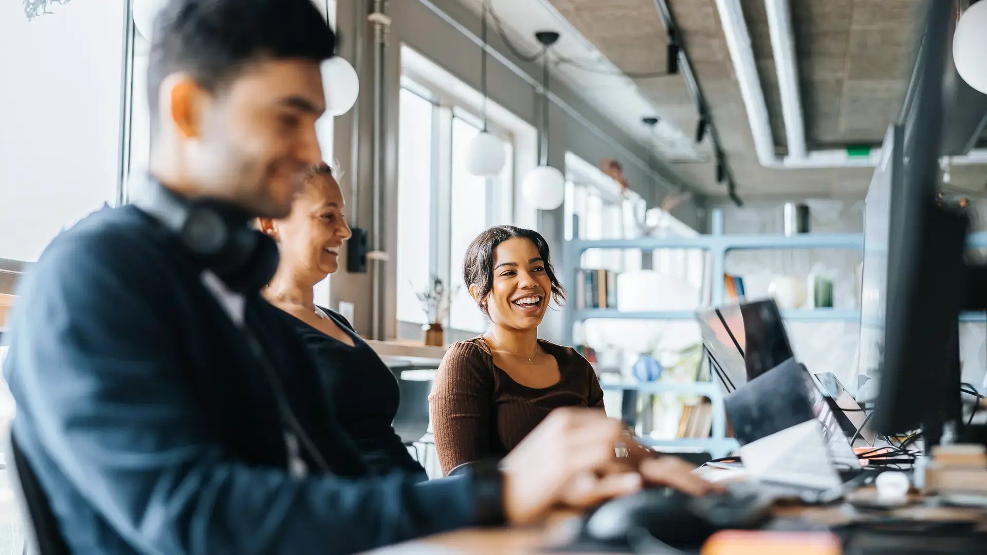 Glada kollegor arbetar vid sina datorer och samarbetar för att optimera verksamhetsprocesser med hjälp av tjänstelagret.