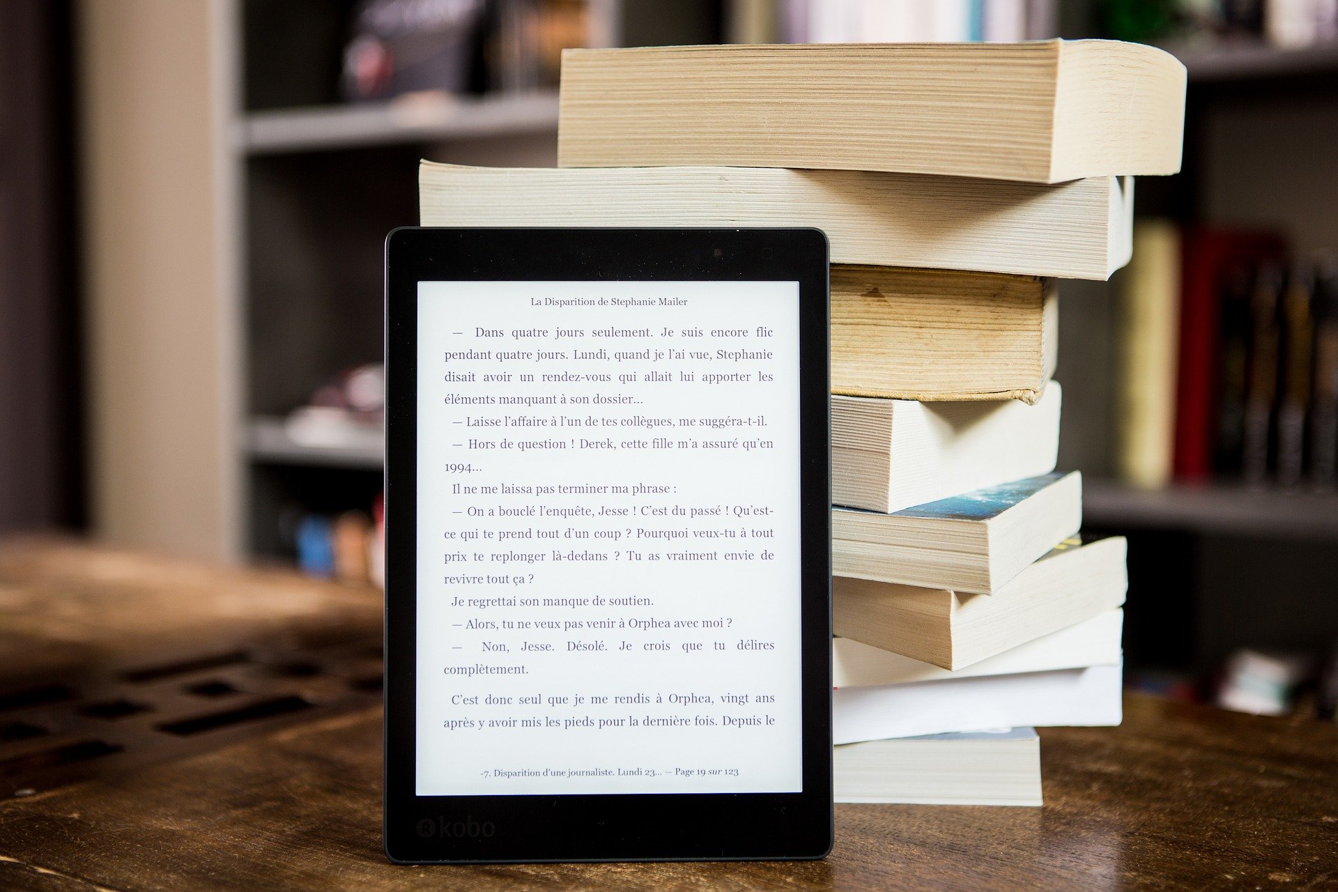 Böcker staplade på hög och en online bok på en ipad