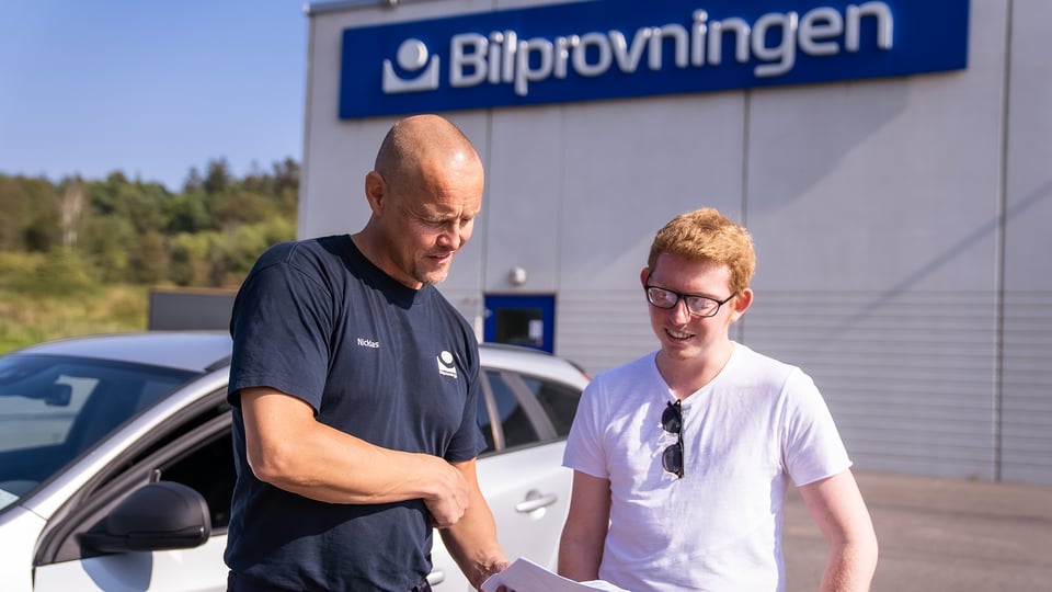 Två män som står utanför Bilprovningen 